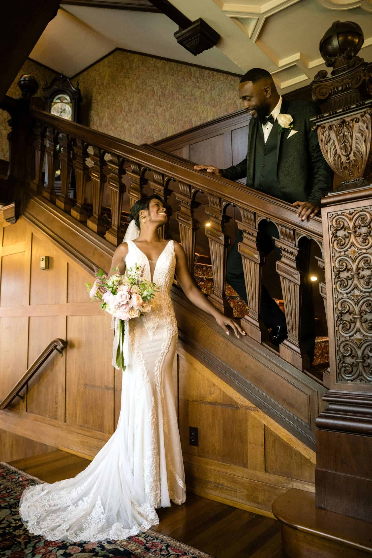 Bride and groom on staircase during wedding ceremony at historic venue.