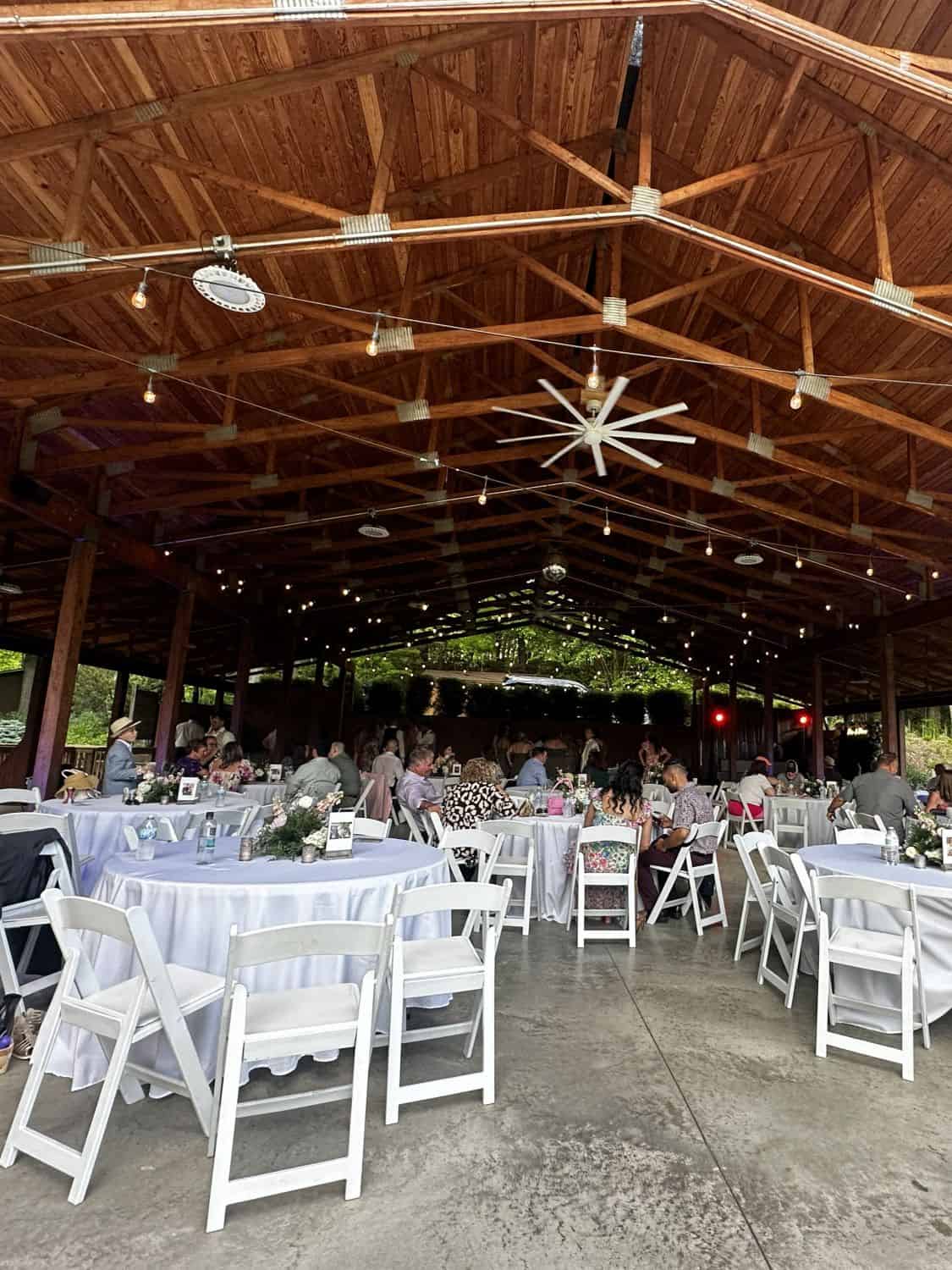 Outdoor event space with wooden ceiling, tables, and chairs for wedding or celebration.
