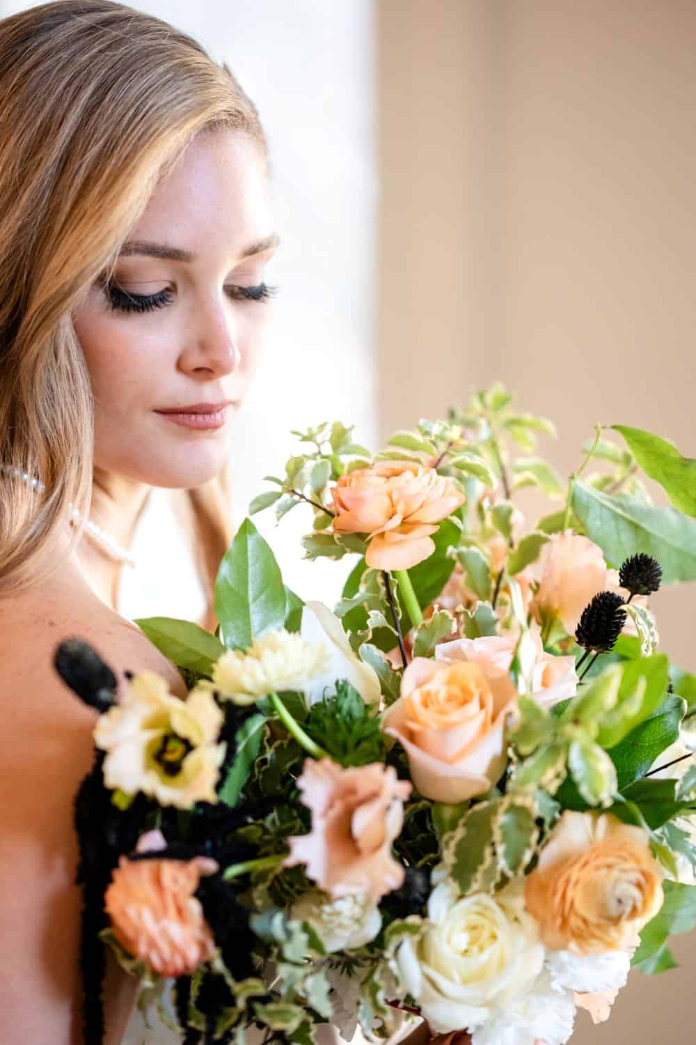 Beautiful bride holding a lush bouquet of roses and greenery.