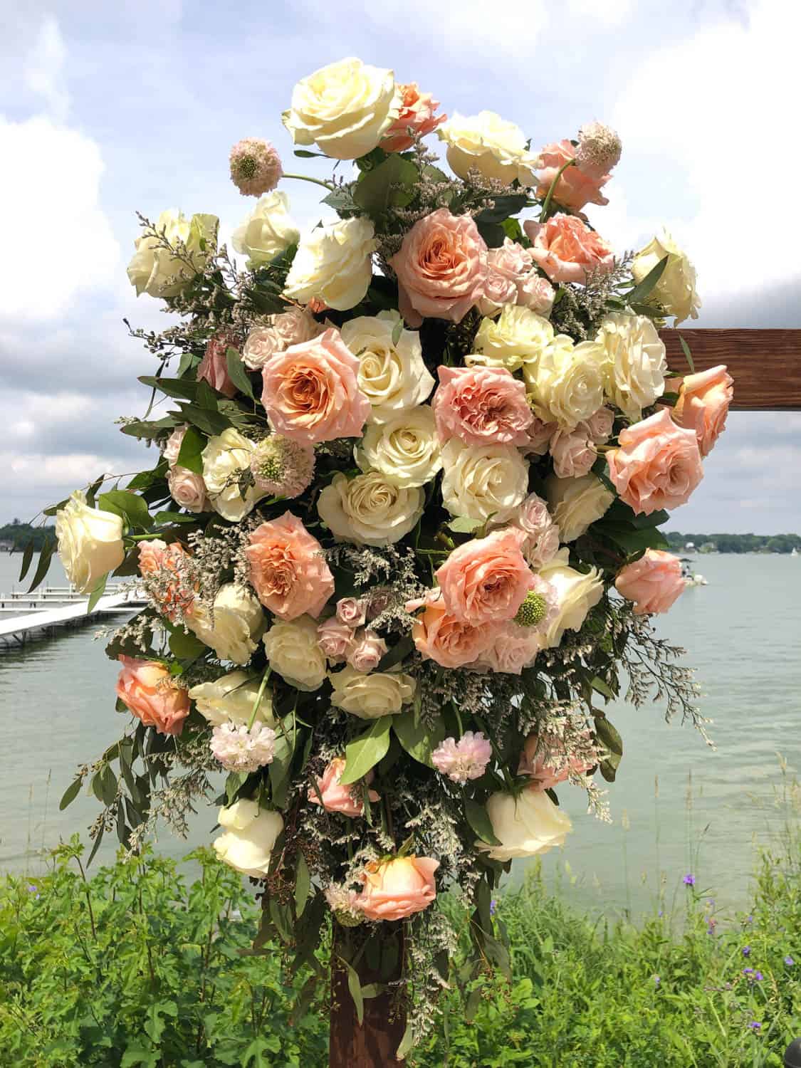 Beautiful wedding floral arrangement with roses and greenery by the water.