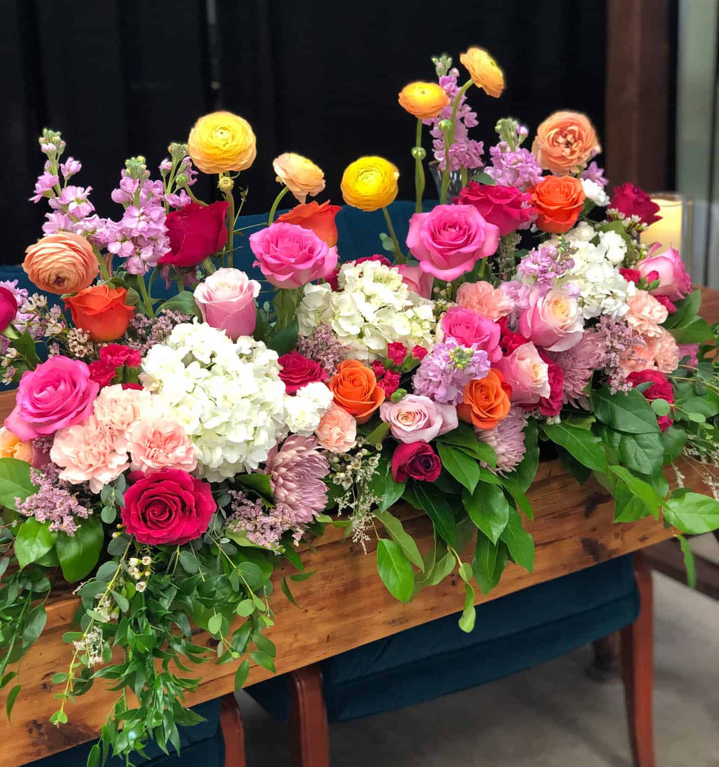 Colorful flower centerpiece with roses, hydrangeas, and ranunculus for event decor.