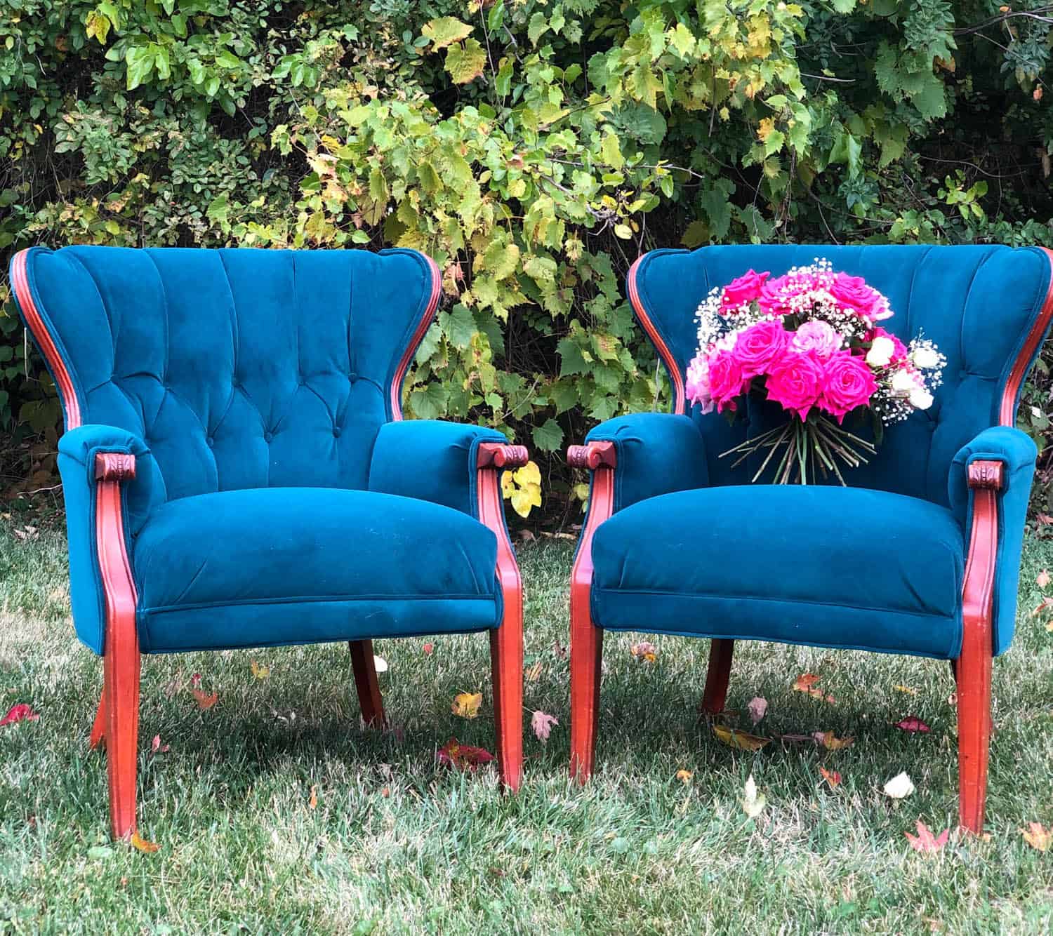 Two blue velvet chairs with pink accents and a floral bouquet for wedding decor.