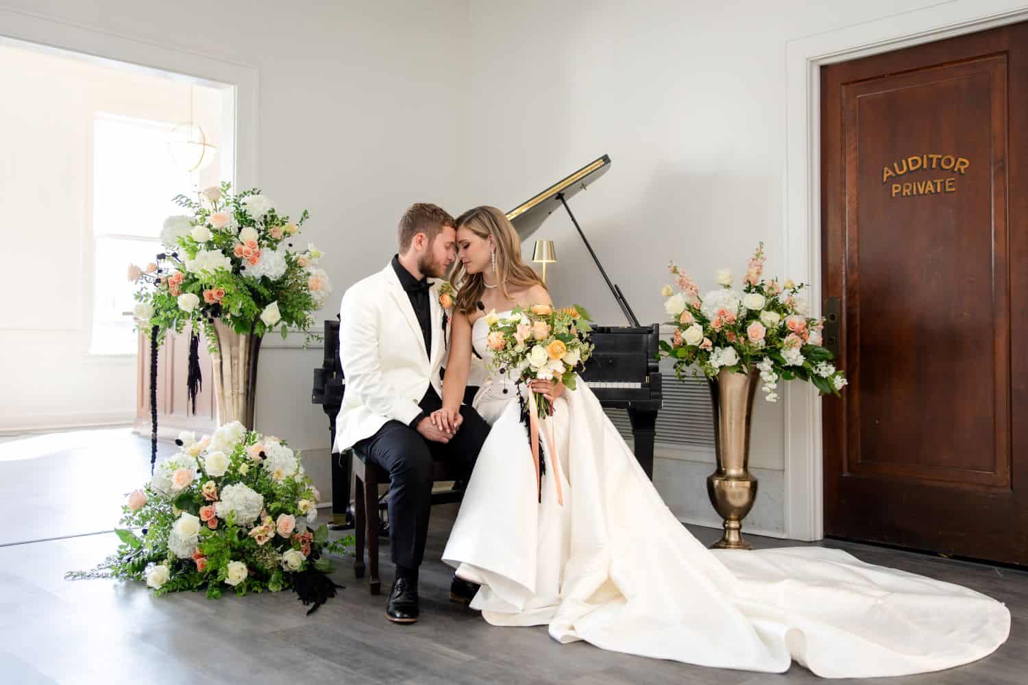 Bride and groom sitting with floral arrangements in a wedding venue.